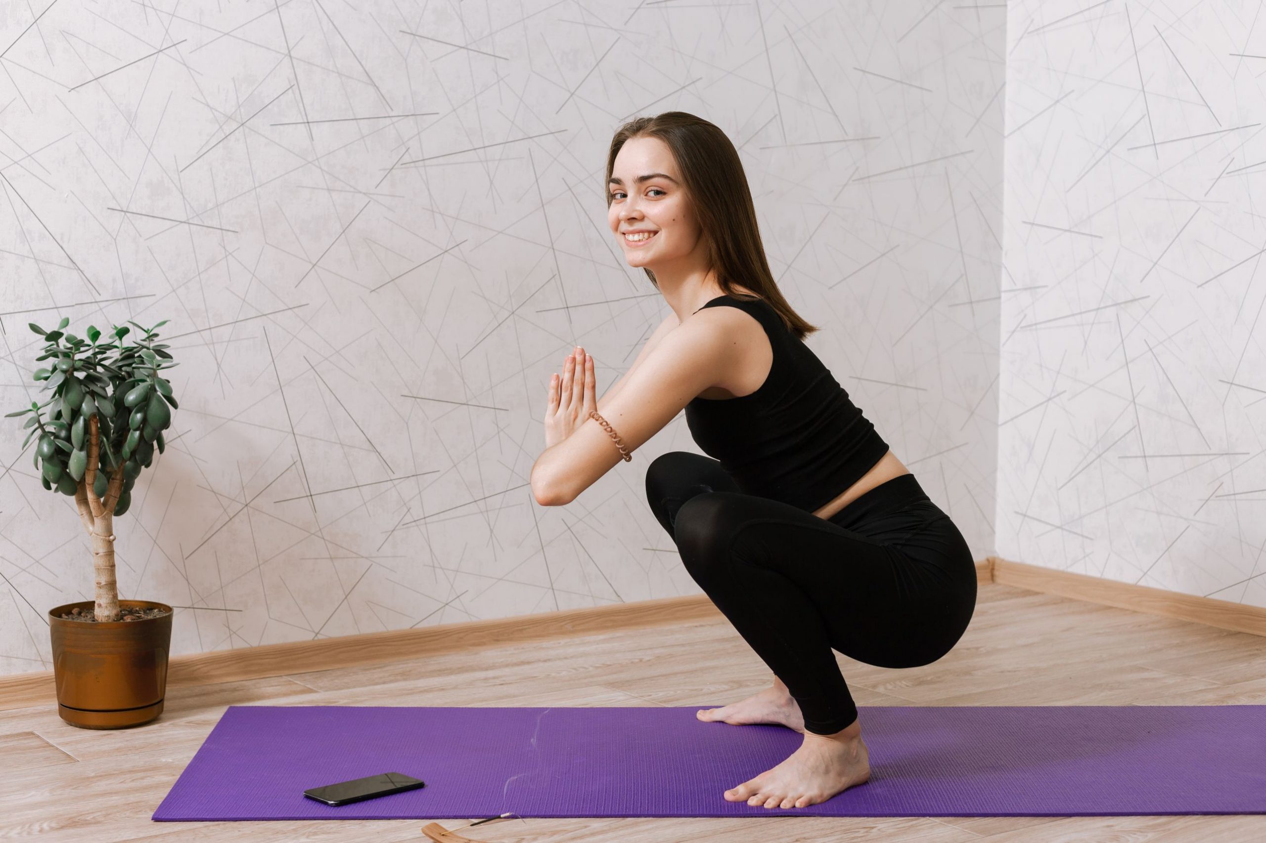 woman-black-activewear-doing-yoga-garland-pose-while-sitting-mat (1)